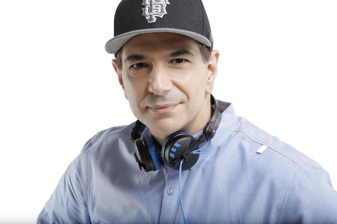 St. John wearing an SF Giants cap with headphones around his neck